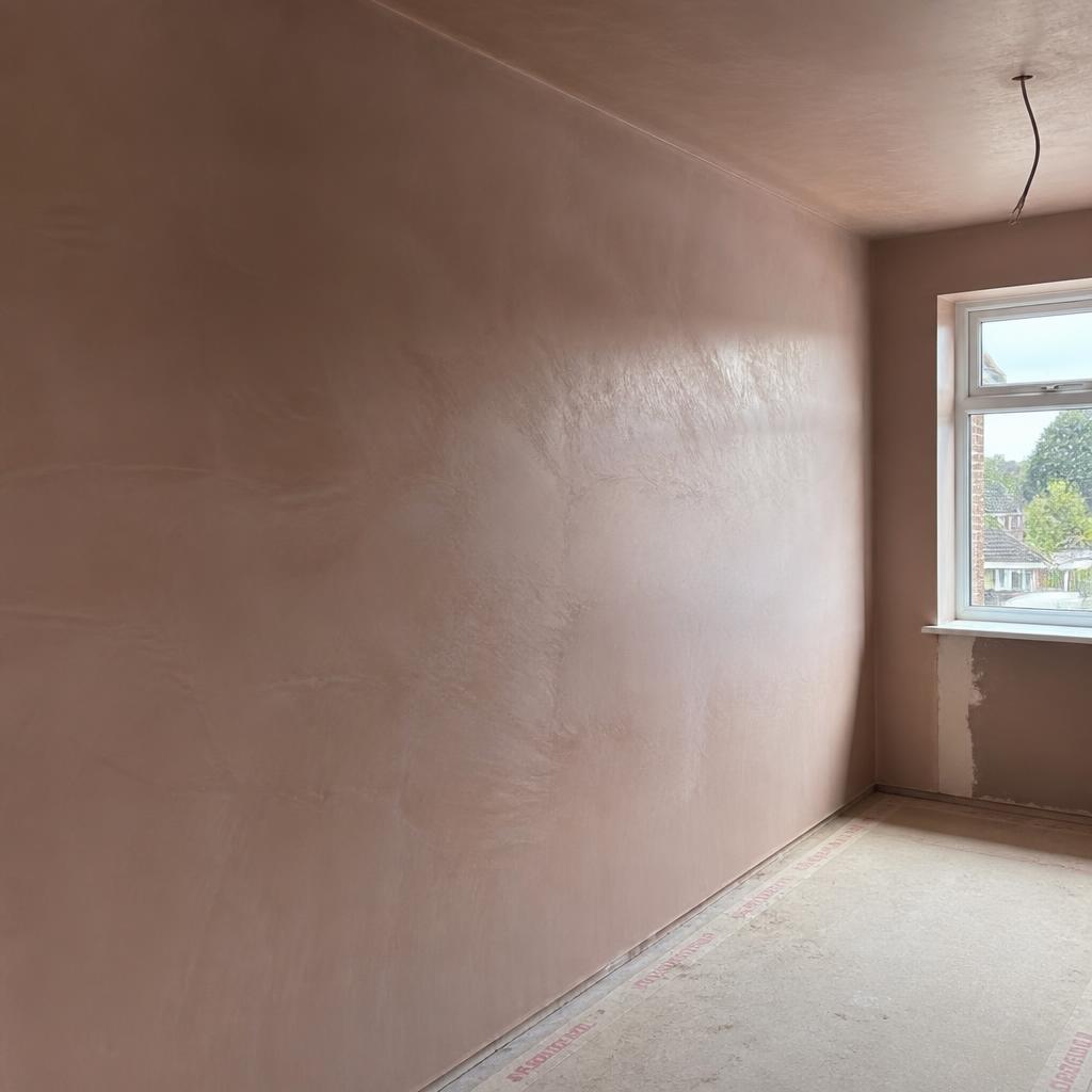 Freshly skimmed pink plaster wall drying in a Shrewsbury home